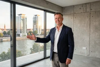 Agent immobilier présentant un appartement neuf avec vue sur Lyon et le Rhône, illustrant l'investissement dans l'immobilier neuf