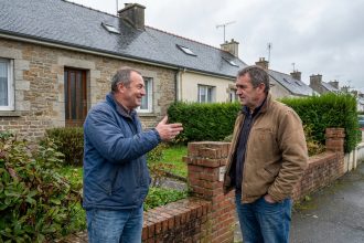 Deux voisins discutent devant un mur en briques à Brest